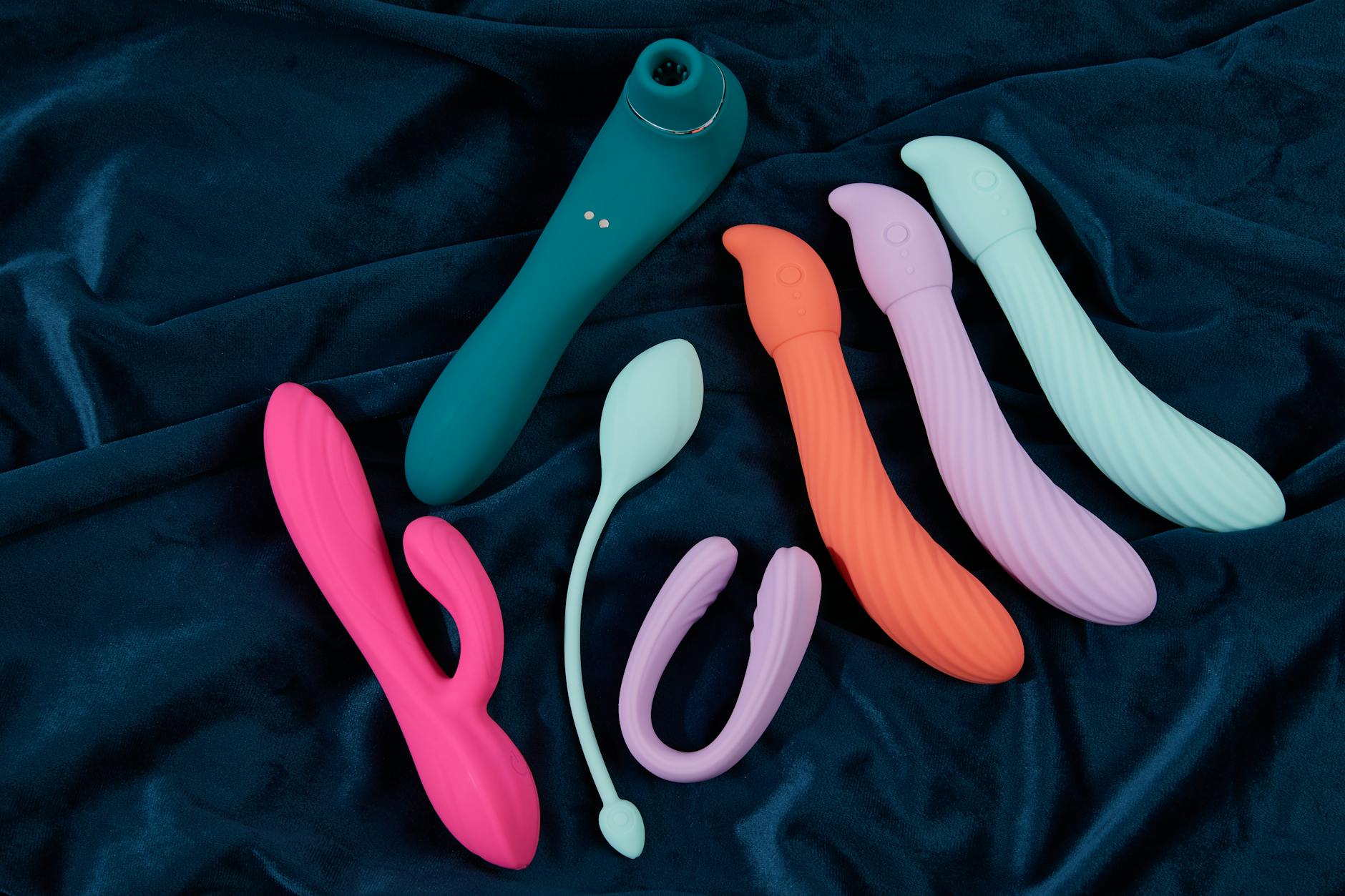 A hand holding a silicone vibrator against a purple background, representing self-pleasure and intimacy.