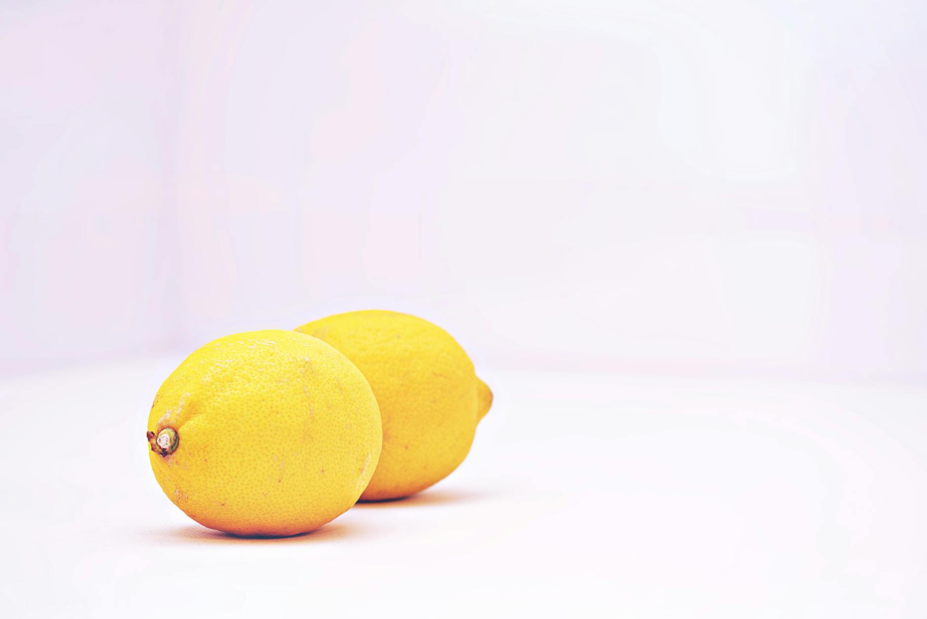 Vibrant yellow lemons on a minimalist white background, symbolizing freshness and renewed pleasure