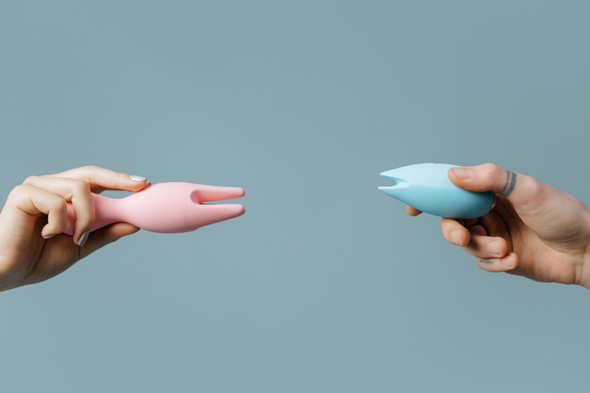 Close-up of hands holding a sleek blue vibrator against a purple background
