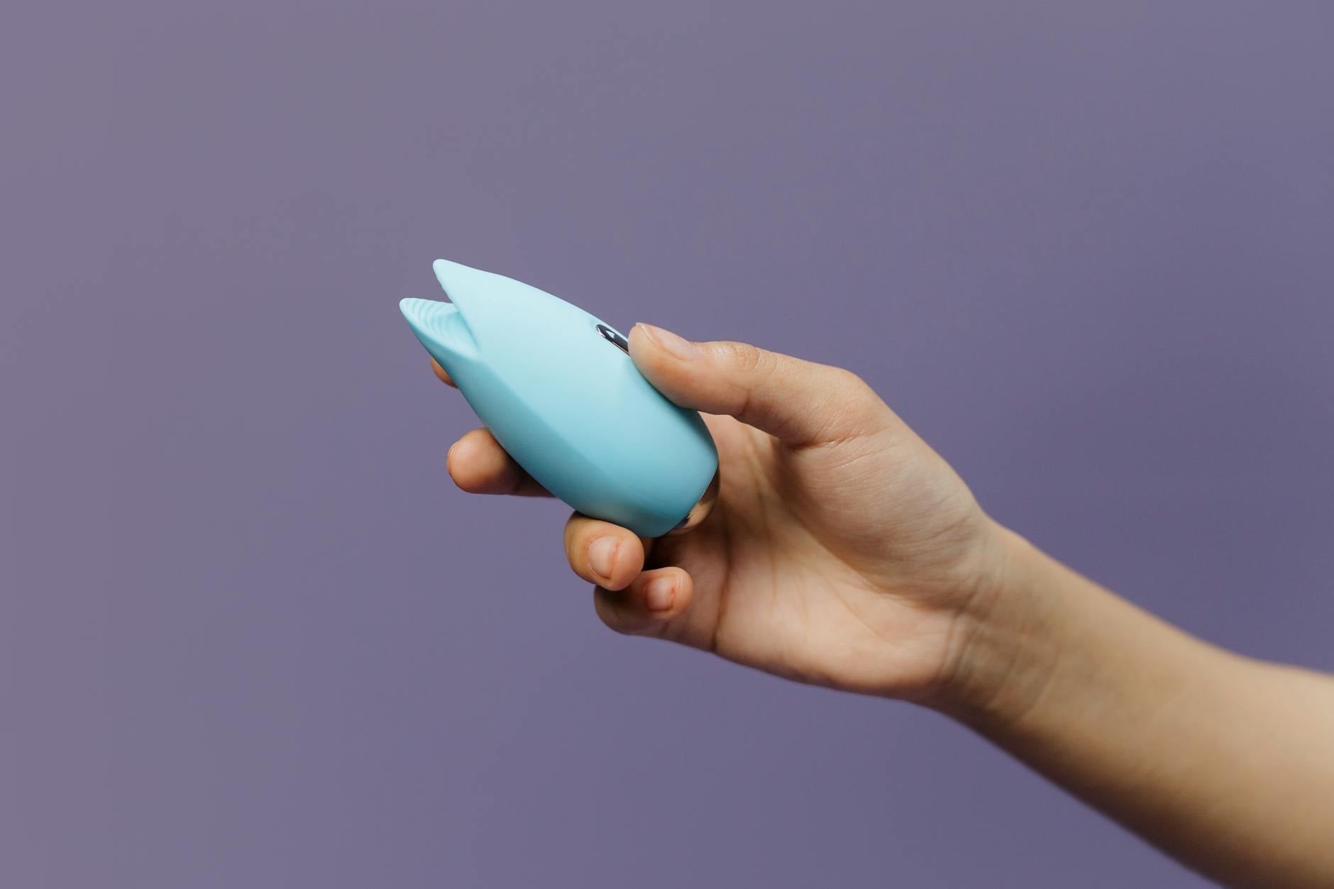 A lemon vibrator held in hand against a purple background, promoting sexual wellness and self-pleasure