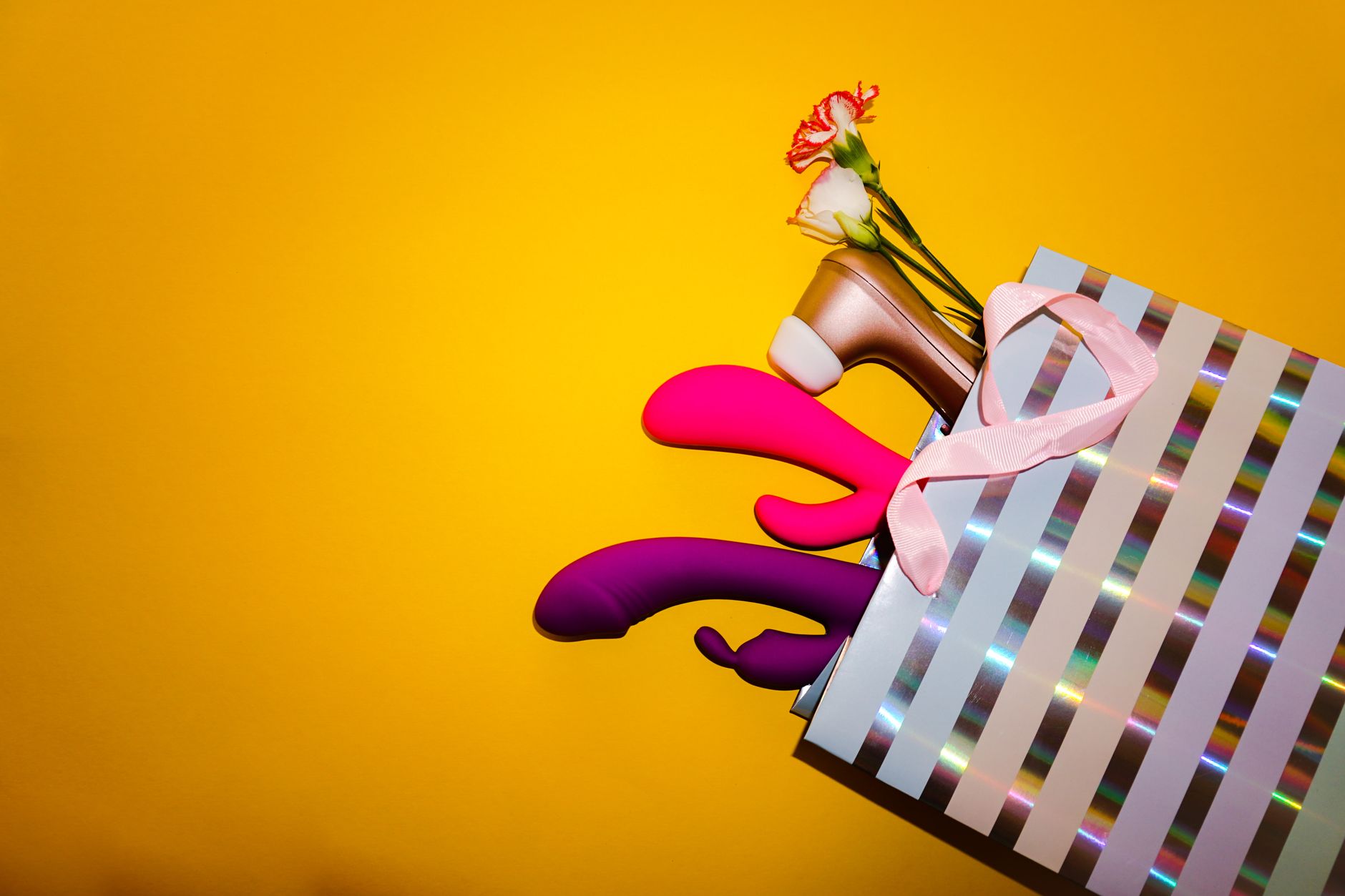 A person holding a basket containing colorful vibrators and a pink flower.