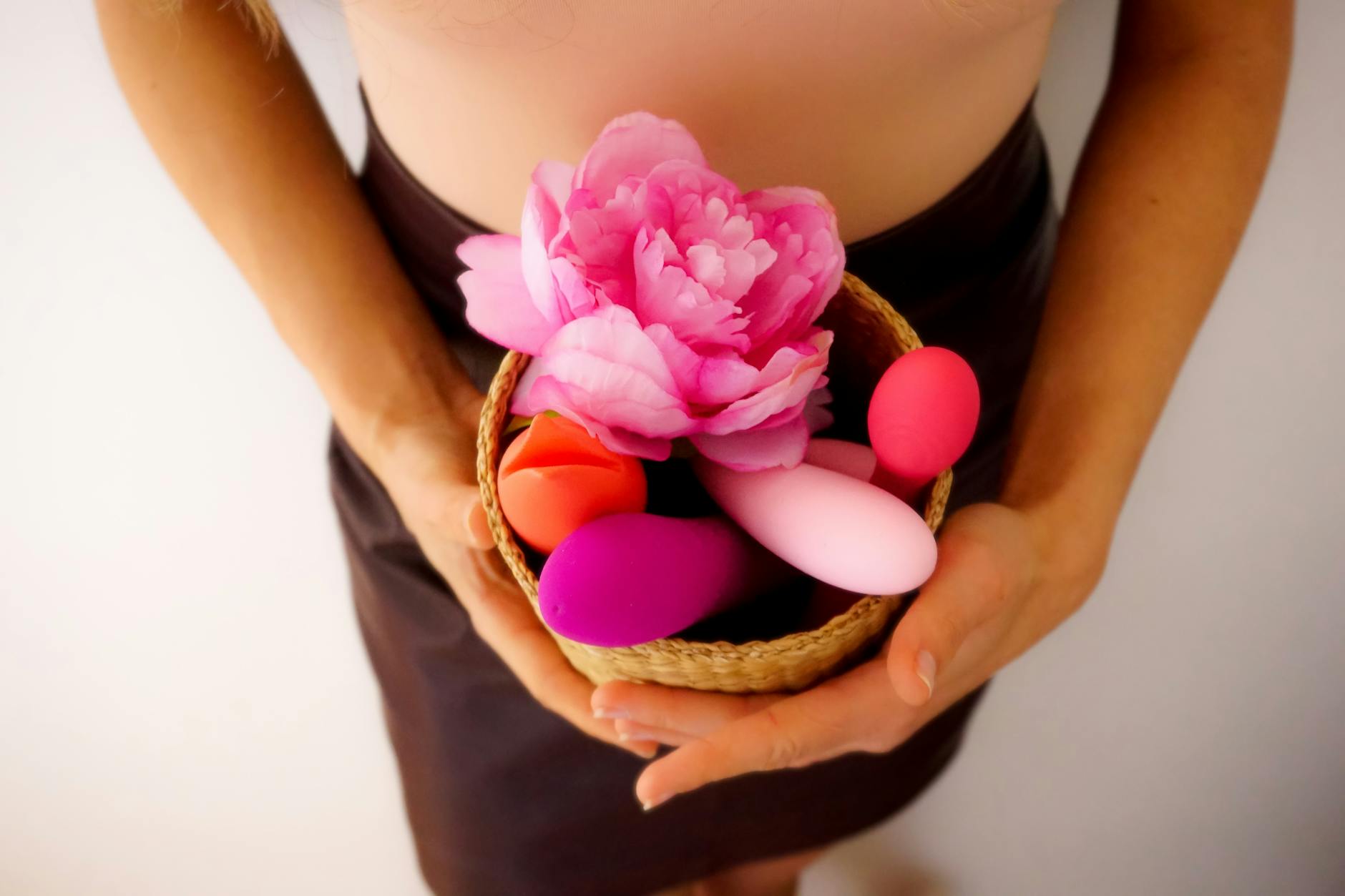Hands holding pastel-colored silicone toys and lemon vibrators for intimate pleasure
